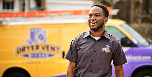 Smiling technician walking with van in background.